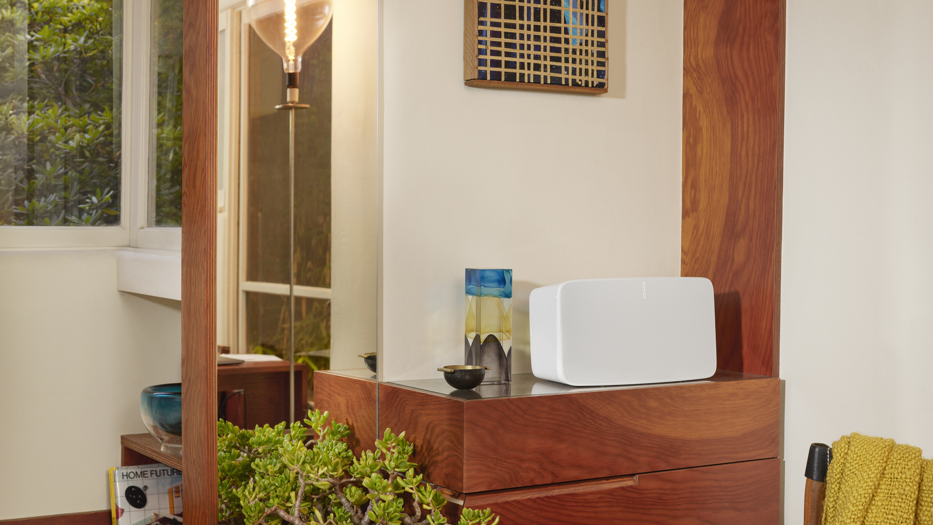 Marin living room at dusk with a compact Sonos speaker on the console — music that stays grouped across the open kitchen beyond